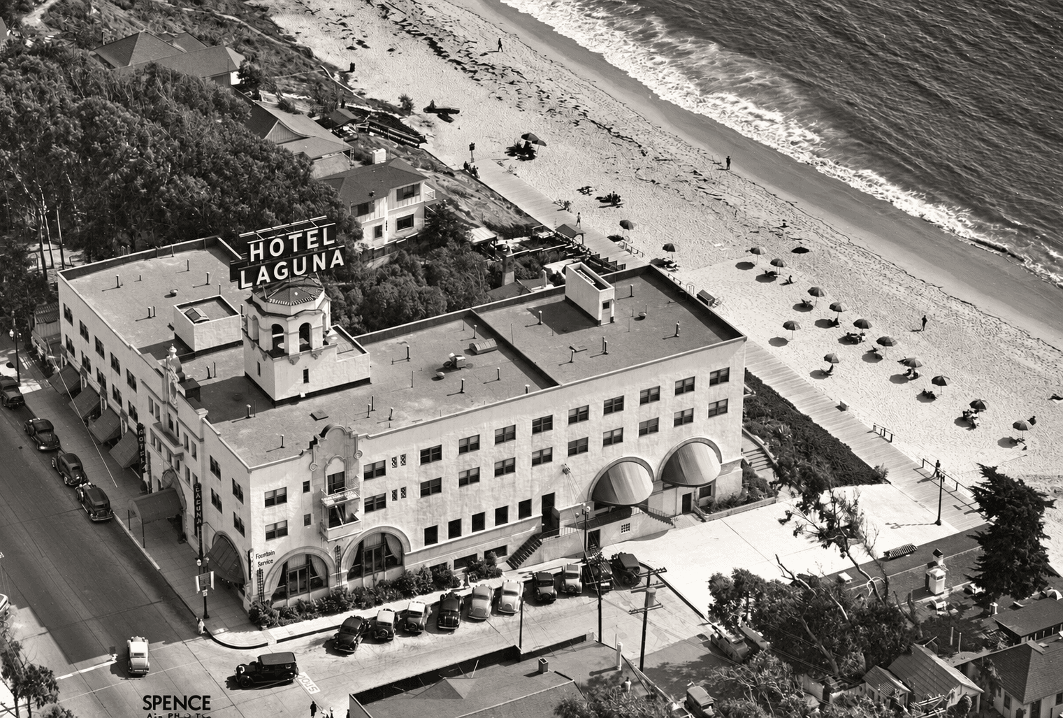 Historic aerial view of Hotel Laguna beside the beach and Pacific Ocean in downtown Laguna Beach.