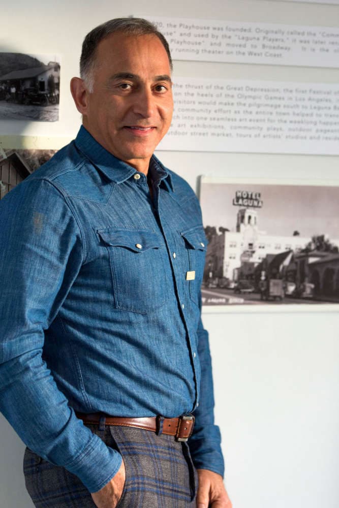 Mo Honarkar standing before a wall of Laguna Beach history panels, an archival photograph of Hotel Laguna beside him.